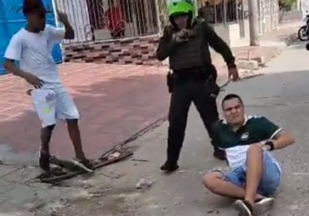 El hombre ya herido en el piso tras el disparo del uniformado que lo grababa cuando intentaba atacarlo con piedras