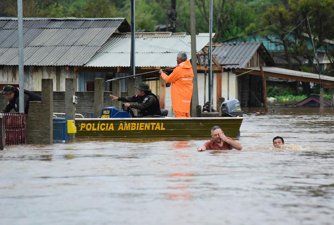 Agentes de policía revisan una casa mientras habitantes vadean una calle inundada por tormentas derivadas de un ciclón en Passo Fundo, en el estado de Rio Grande do Sul, Brasil, el lunes 4 de septiembre de 2023. (AP Foto/Diogo Zanatta-Futura Press)