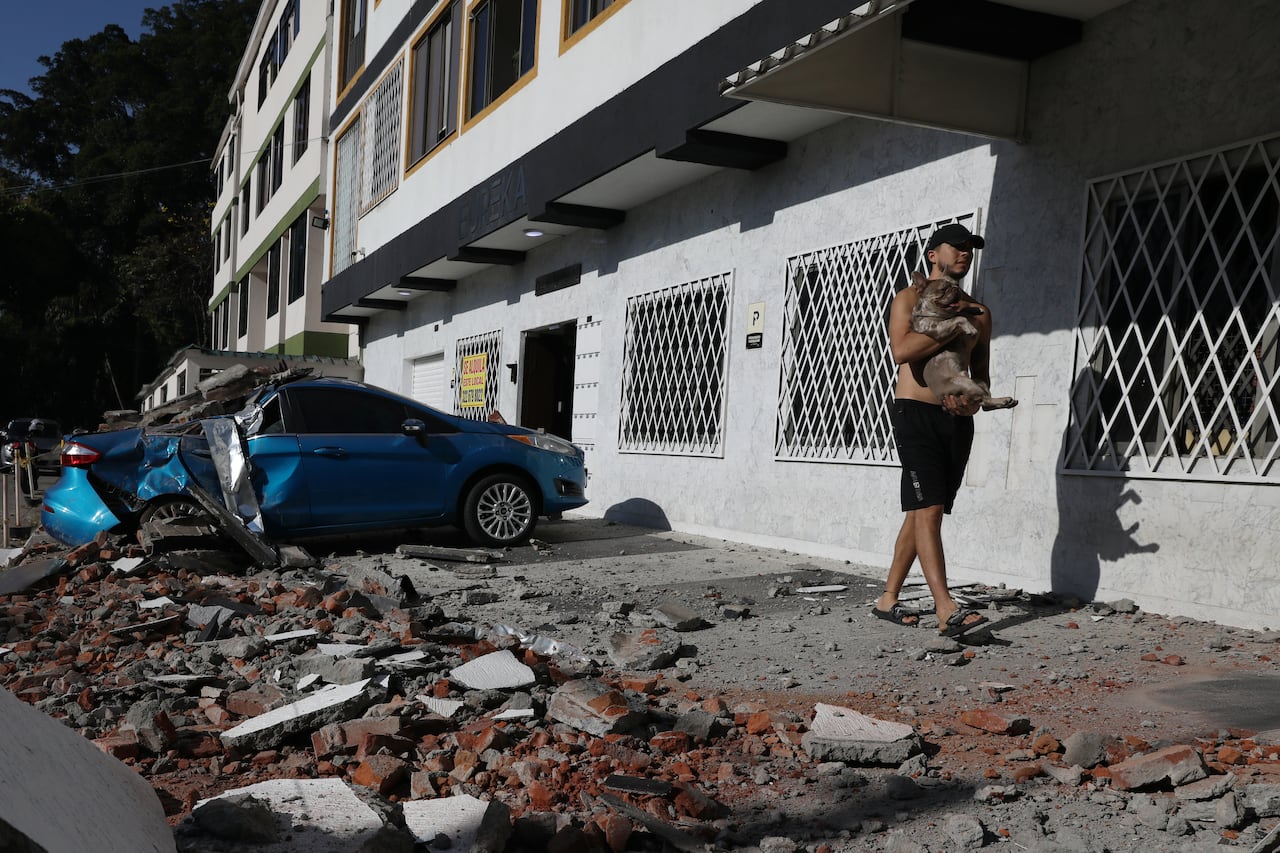 Un hombre carga a su perro después de que un terremoto azotara Cali, Colombia, el lunes 10 de agosto de 2026.