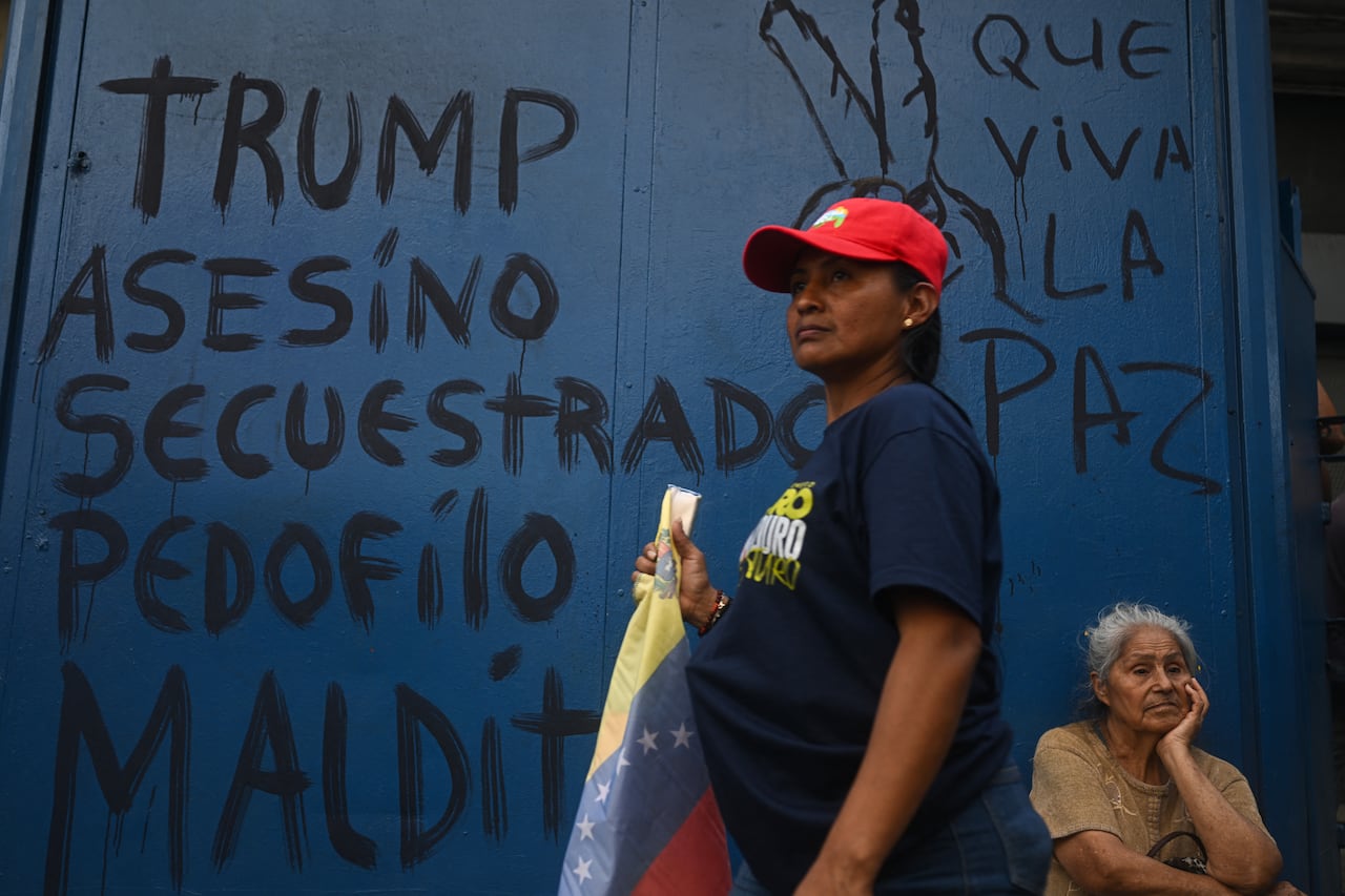 Mujeres pasan frente a un grafiti anti-Trump que dice "¡Viva la paz!" durante una manifestación en apoyo al derrocado presidente venezolano, Nicolás Maduro, y a su esposa, Cilia Flores