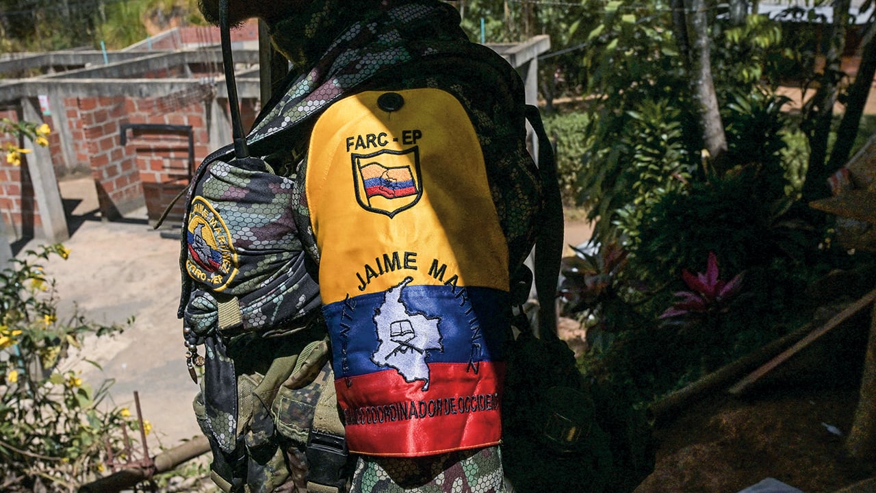Un guerrillero de la disidencia de las FARC «Jaime Martínez» hace guardia mientras el comandante Andrey concede una entrevista cerca del municipio de Suárez, en el departamento del Cauca, el 30 de agosto de 2023. El grupo disidente EMC, que rechazó el acuerdo de paz de 2016 que condujo al desarme de las FARC, iniciará conversaciones de paz directas con el Gobierno colombiano el 31 de agosto. (Photo by JOAQUIN SARMIENTO / AFP)
