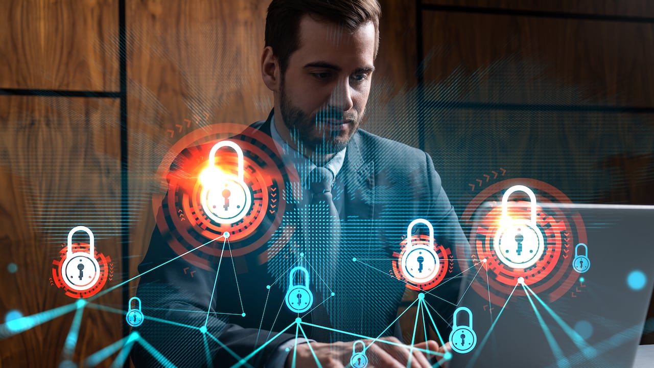 Businessman in office working with laptop, develop data protection system to diminish business risks, typing computer. Double exposure.
