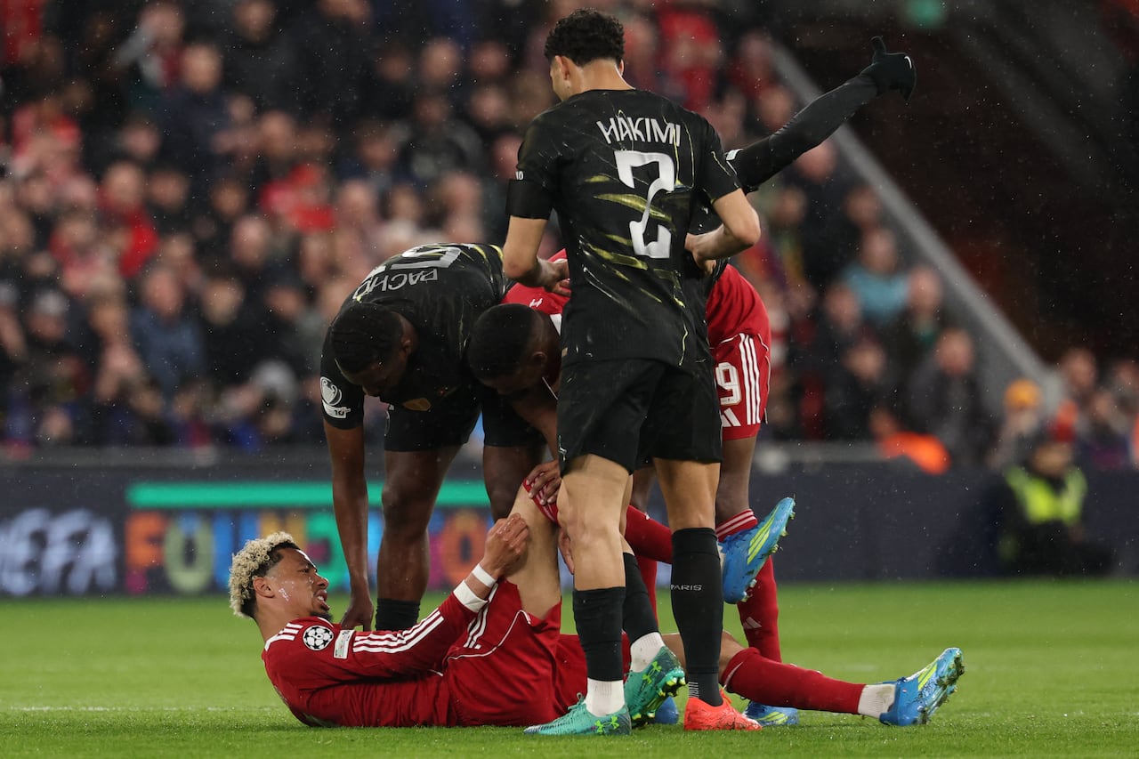 Los jugadores atienden al delantero francés del Liverpool, Hugo Ekitike, número 22, que yace lesionado durante el partido de vuelta de los cuartos de final de la Liga de Campeones de la UEFA entre el Liverpool y el Paris Saint-Germain en Anfield, Liverpool, al noroeste de Inglaterra, el 14 de abril de 2026. (Foto de FRANCK FIFE / AFP)