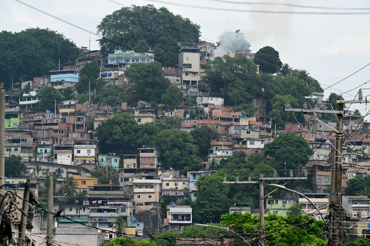 El 29 de octubre de 2025, tras la Operación Contención, se observa humo saliendo de una casa en la favela Vila Cruzeiro, en el complejo Penha de Río de Janeiro, Brasil. Según informó la AFP, los residentes de la favela alinearon más de 50 cuerpos en una plaza de su barrio de bajos ingresos ese mismo día, un día después de la operación policial más sangrienta en la historia de la ciudad. (Foto de Pablo Porciúncula / AFP)