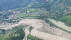 Las imágenes muestran una espesa capa de lodo y escombros de las inundaciones que cubren partes de un valle fluvial en el distrito de Rasuwa, con tierras de cultivo y asentamientos dispersos por las laderas circundantes.