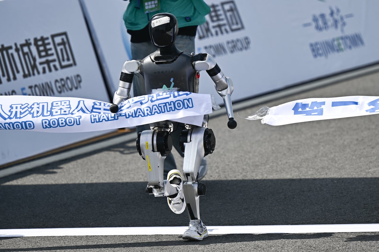 Un robot cruza la meta en la media maratón de robots humanoides en Pekín el 19 de abril de 2025. Decenas de robots humanoides recorrieron las calles de Pekín, uniéndose a miles de sus homólogos de carne y hueso en una media maratón pionera a nivel mundial que demostró el impulso de China por liderar la carrera global en tecnología de vanguardia. (Foto de Pedro PARDO / AFP)