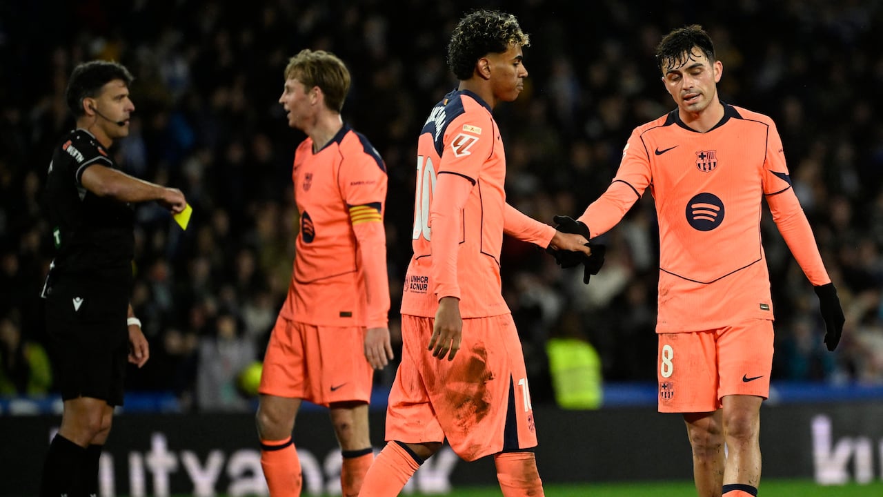 El centrocampista español #08 del Barcelona, Pedri, y el delantero español #10 del Barcelona, Lamine Yamal (2D), se dan la mano mientras el árbitro español Jesús Gil (I) muestra una tarjeta amarilla al delantero holandés #26 del FC Porto, Luuk De Jong, durante el partido de fútbol de la liga española entre la Real Sociedad y el FC Barcelona en el Estadio de Anoeta en San Sebastián el 18 de enero de 2026. (Foto de ANDER GILLENEA / AFP)