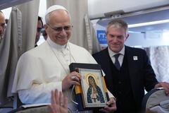 Pope Leo XIV holds an icon as he greets reporters aboard a flight on his way to Ankara on November 27, 2025. Pope Leo XIV arrived in Turkey on the first overseas trip of his papacy, which will also take him to Lebanon. (Photo by Domenico Stinellis / POOL / AFP)