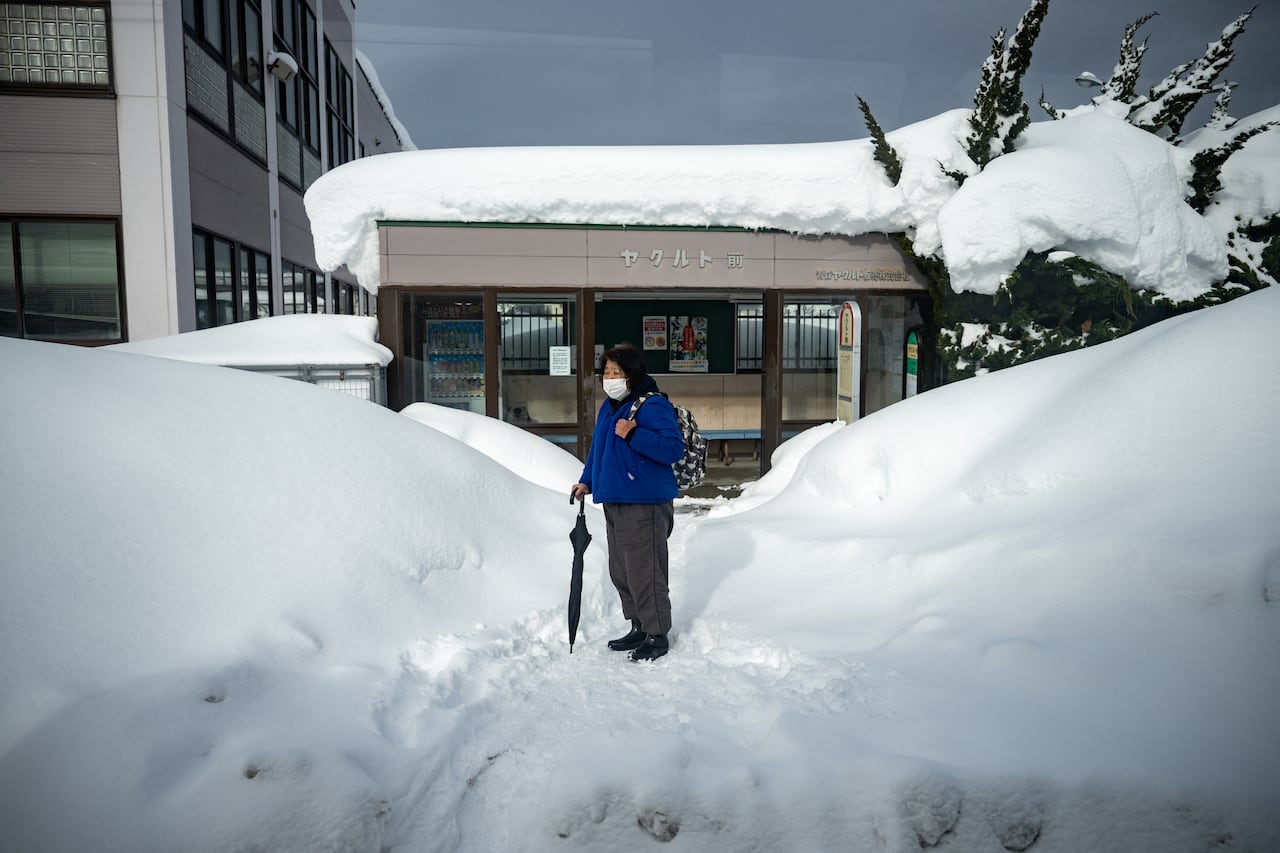 This picture taken through the window of a bus shows a passenger waiting in front of a snow covered bus stop in Aomori city, Aomori prefecture on January 30, 2026. (Photo by Philip FONG / AFP)