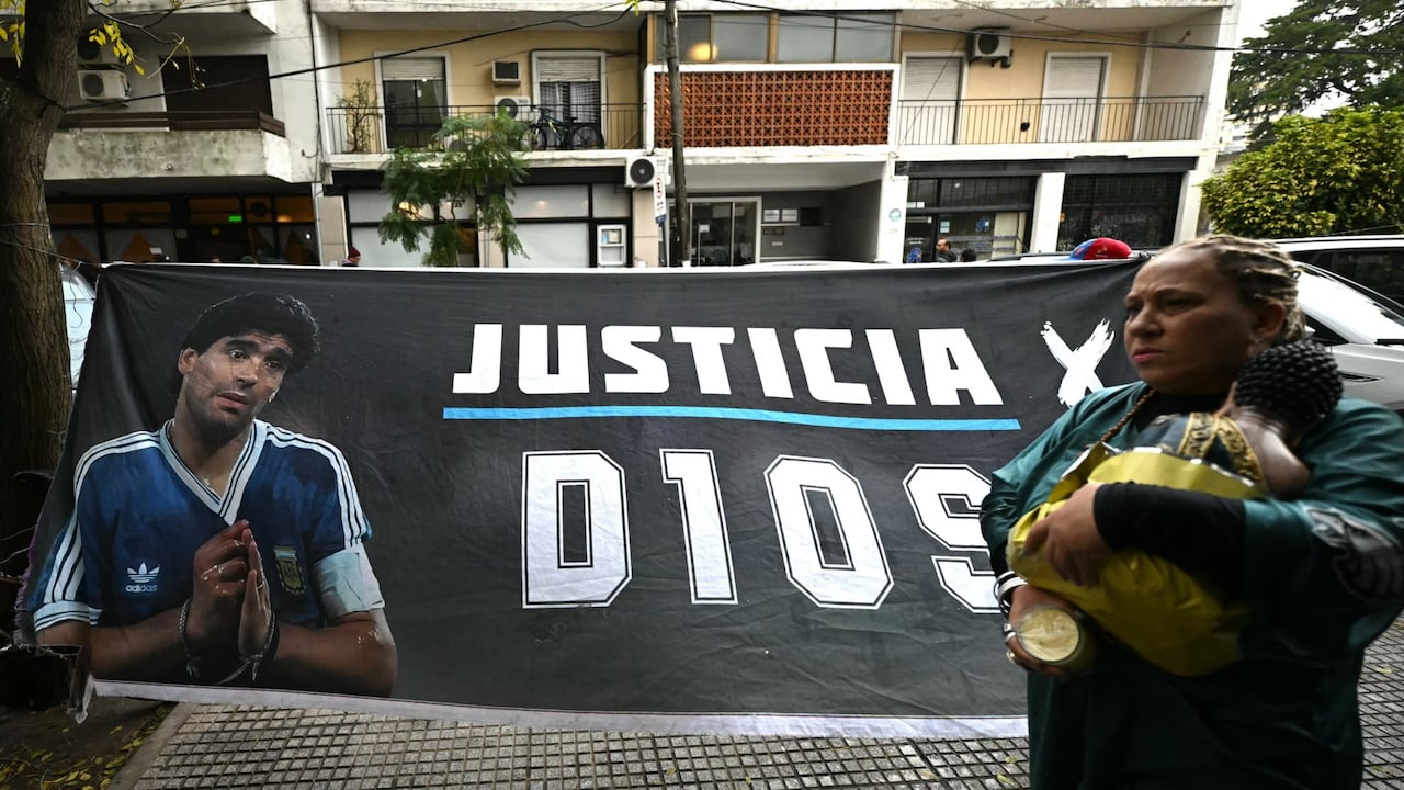 Una mujer pasa junto a una pancarta que muestra al legendario futbolista argentino Diego Maradona y exige justicia frente al tribunal antes de la audiencia sobre su muerte en San Isidro, provincia de Buenos Aires, Argentina, el 9 de junio de 2026.