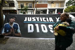 Una mujer pasa junto a una pancarta que muestra al legendario futbolista argentino Diego Maradona y exige justicia frente al tribunal antes de la audiencia sobre su muerte en San Isidro, provincia de Buenos Aires, Argentina, el 9 de junio de 2026.