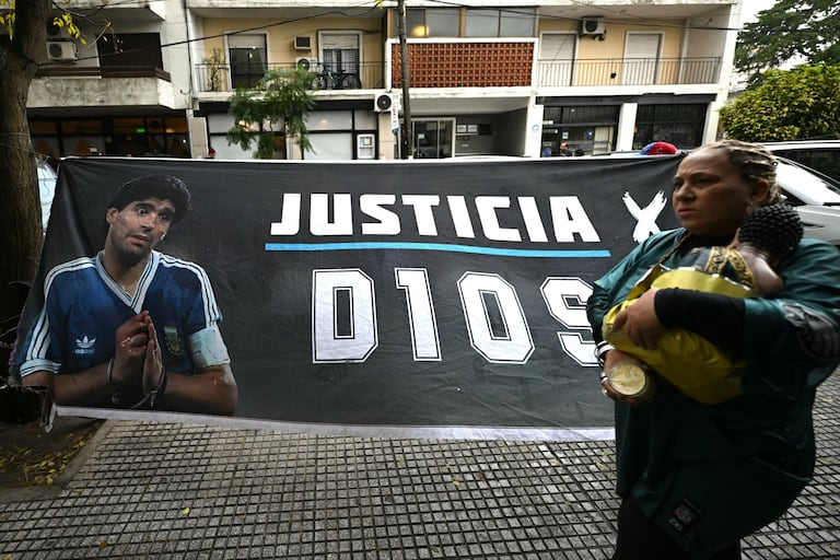 Una mujer pasa junto a una pancarta que muestra al legendario futbolista argentino Diego Maradona y exige justicia frente al tribunal antes de la audiencia sobre su muerte en San Isidro, provincia de Buenos Aires, Argentina, el 9 de junio de 2026.