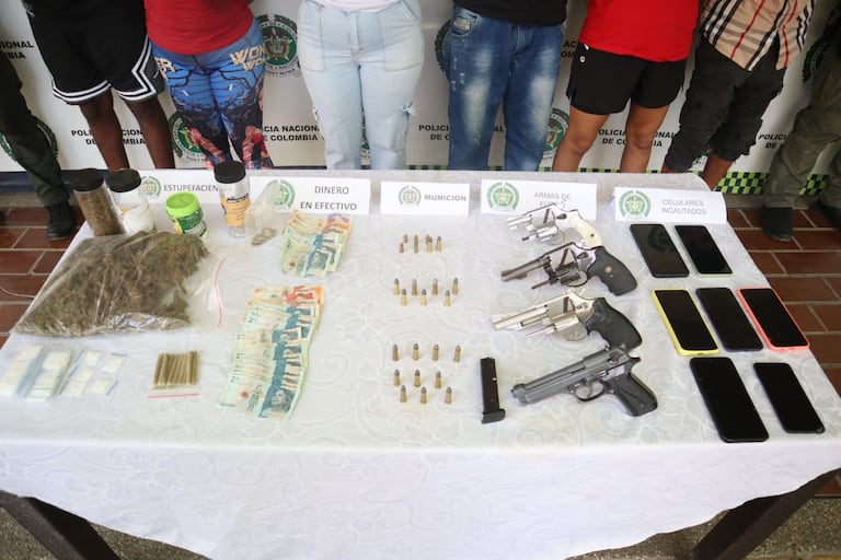Las cuatro armas de fuego, municiones, dinero en efectivo y estupefacientes incautados por las autoridades durante los operativos en la Comuna 16.