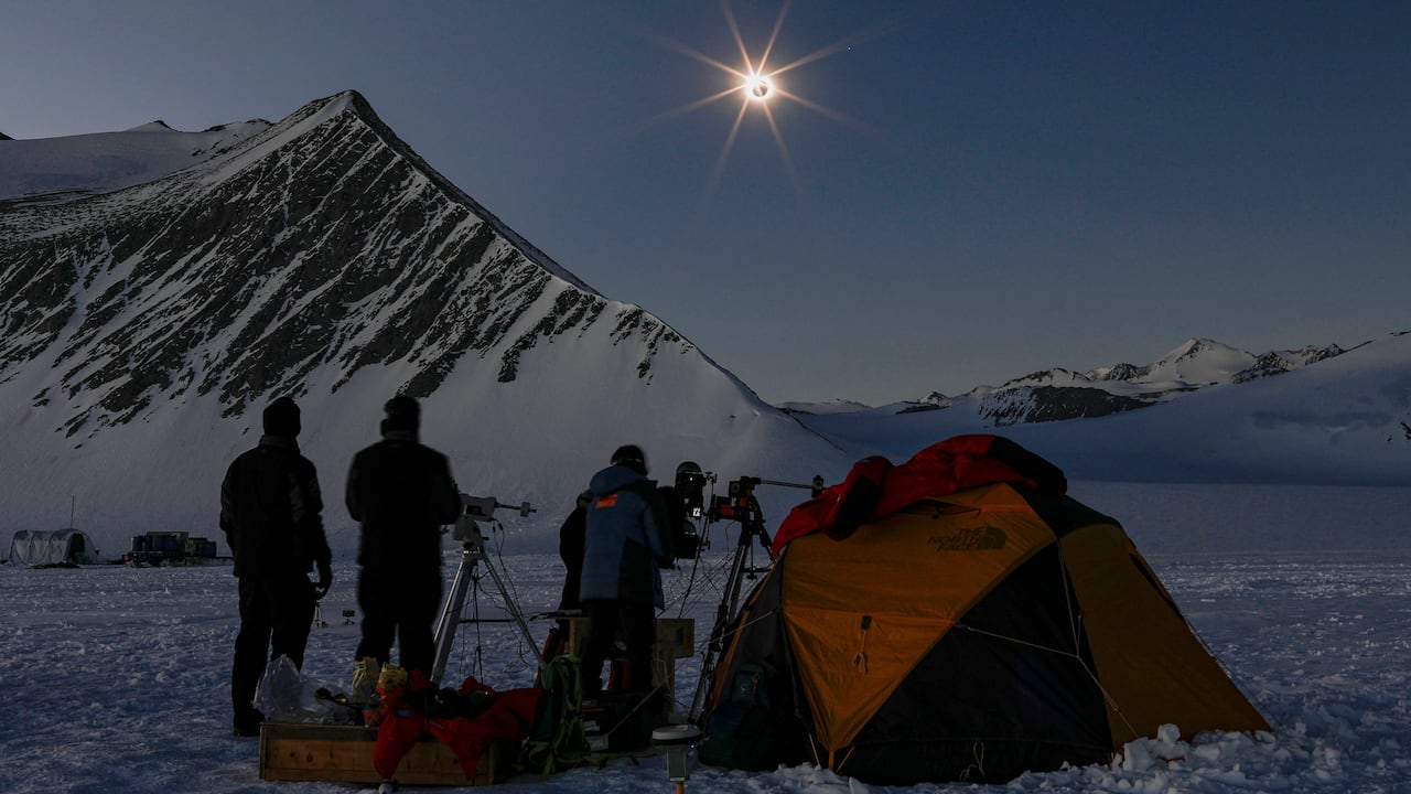 Científicos chilenos y estadounidenses mirando un eclipse solar desde el glaciar Unión en la Antártida el 4 de diciembre de 2021. (Foto por FELIPE TRUEBA / Imagen Chile / AFP)