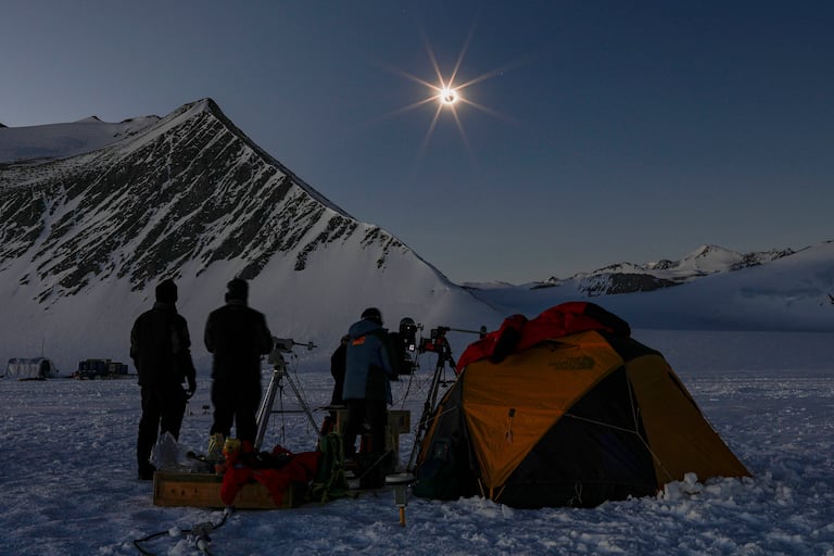 Científicos chilenos y estadounidenses mirando un eclipse solar desde el glaciar Unión en la Antártida el 4 de diciembre de 2021. (Foto por FELIPE TRUEBA / Imagen Chile / AFP)