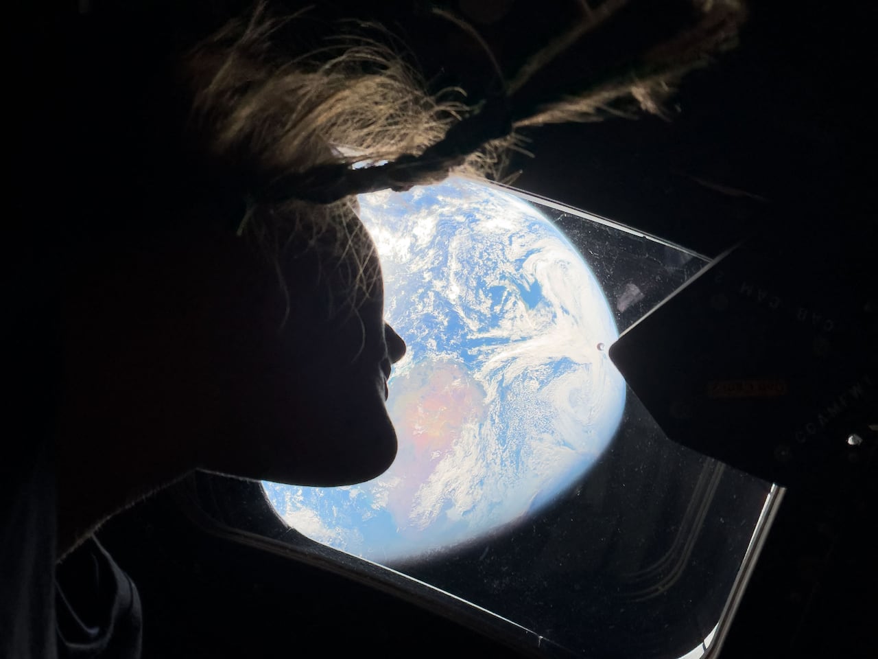 This handout picture by an Artemis II crew member provided by NASA shows Artemis II mission specialist Christina Koch looking back at earth through the window of the Orion spacecraft on April 2, 2026. The four Artemis astronauts have passed the halfway point between Earth and the Moon on the way to their planned lunar flyby, NASA said on April 3. "You are now closer to the moon than you are to us on Earth," mission control told the astronauts at around 11 pm (0400 GMT), according to the space agency's official live broadcast. (Photo by Handout / NASA / AFP) / RESTRICTED TO EDITORIAL USE - MANDATORY CREDIT "AFP PHOTO / NASA" - HANDOUT - NO MARKETING NO ADVERTISING CAMPAIGNS - DISTRIBUTED AS A SERVICE TO CLIENTS