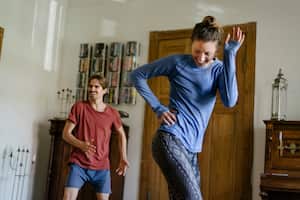 Una pareja joven divirtiéndose mientras hace ejercicio aeróbico en casa juntos.