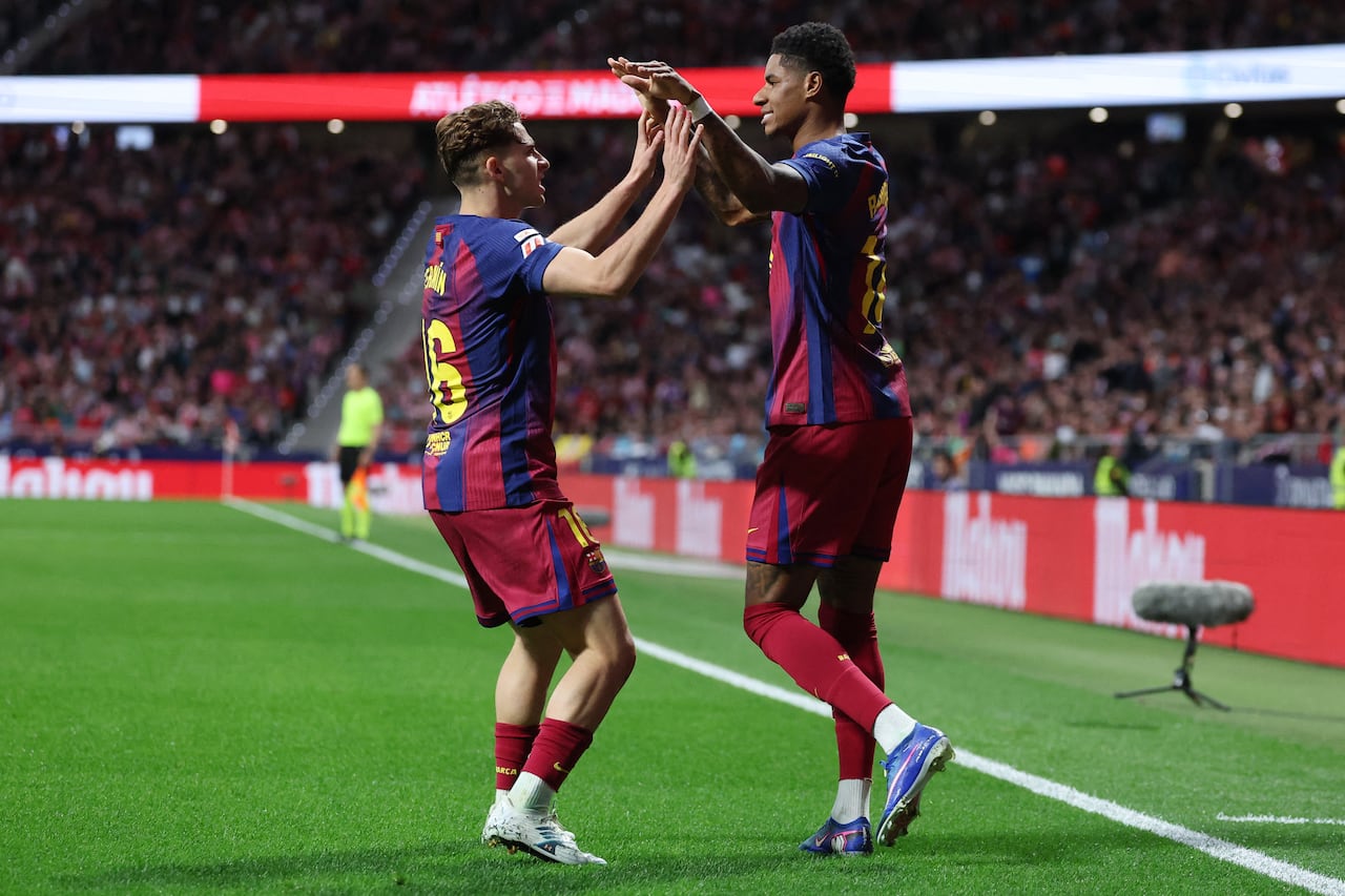 El delantero inglés del Barcelona, Marcus Rashford (derecha), número 14, celebra el primer gol de su equipo con el centrocampista español del Barcelona, Fermín López (número 16), durante el partido de la liga española entre el Club Atlético de Madrid y el FC Barcelona en el Estadio Metropolitano de Madrid el 4 de abril de 2026. (Foto de Pierre-Philippe MARCOU / AFP)