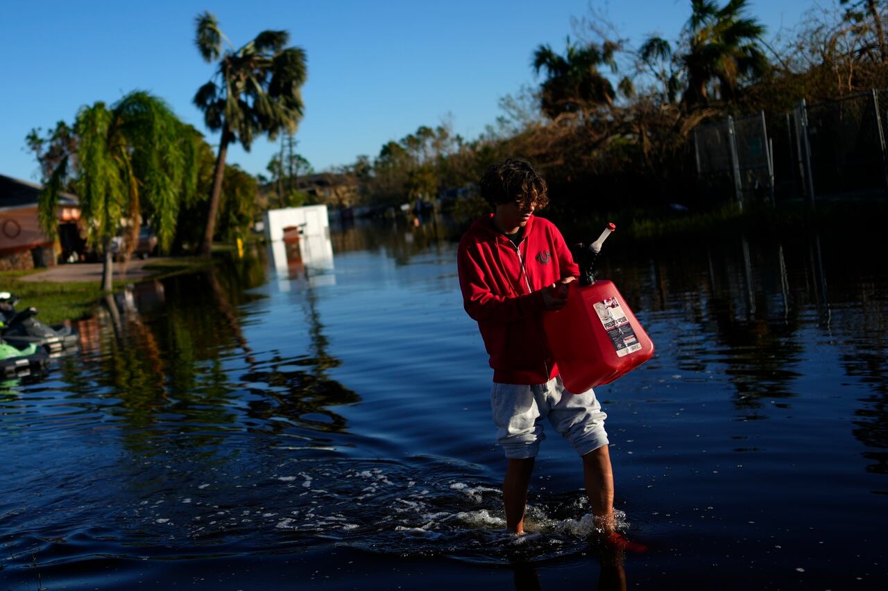 José Cruz, de 13 años, lleva un bidón vacío a través de las aguas de inundación que retroceden frente a su casa mientras su familia sale a buscar suministros, tres días después del paso del huracán Ian, en Fort Myers, Florida