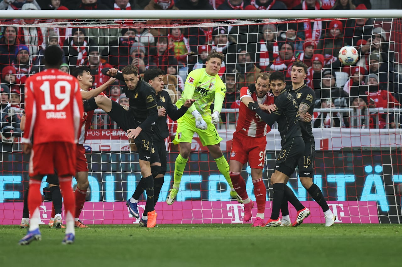 El portero alemán del Augsburgo, #01 Finn Dahmen, salva un balón junto al delantero inglés del Bayern Múnich #09 Harry Kane (2.º por la derecha) durante el partido de la Bundesliga alemana entre el FC Bayern Múnich y el FC Augsburgo en Múnich, sur de Alemania, el 24 de enero de 2026. (Foto de Alexandra BEIER / AFP)