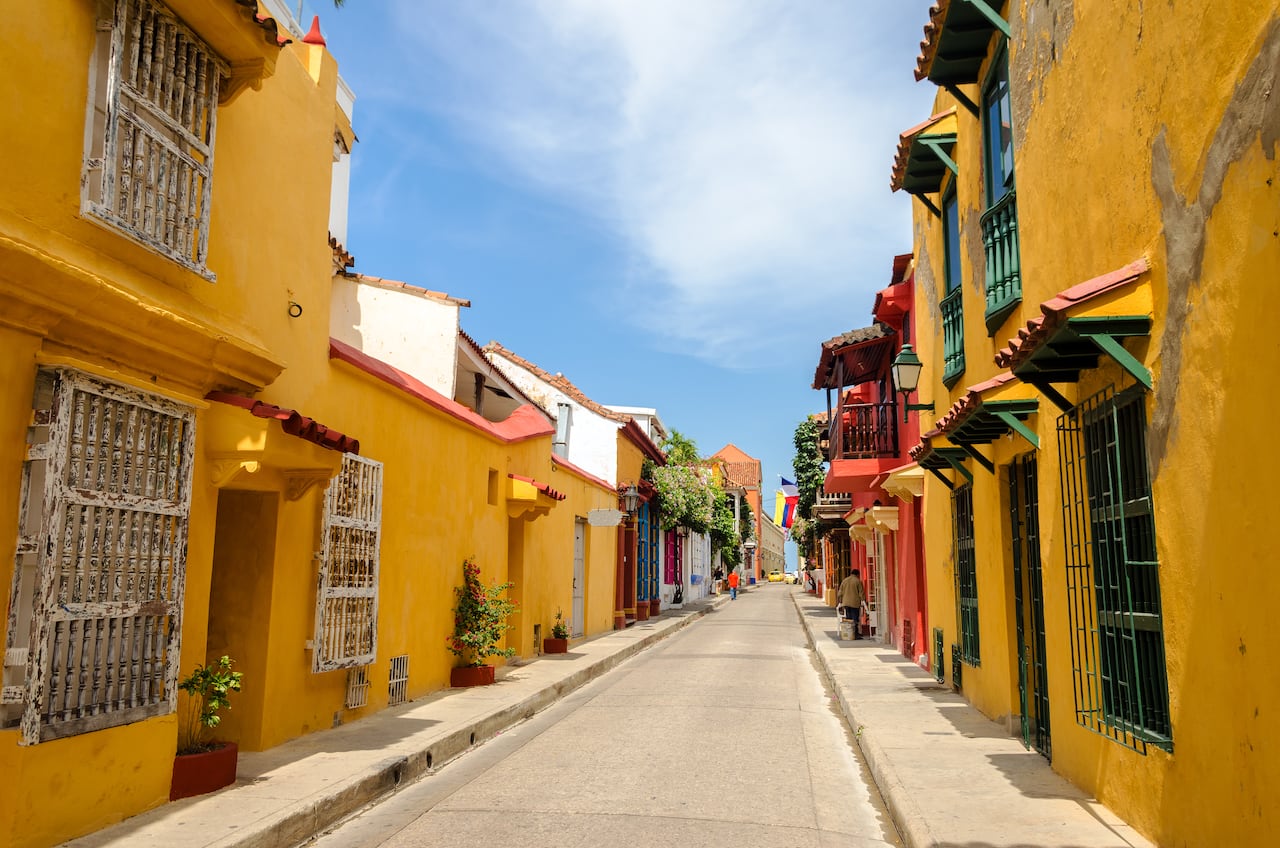 Escena callejera típica en Cartagena, Colombia, de una calle con antiguas casas coloniales históricas a cada lado.