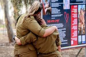 Female Israeli army soldiers embrace as they visit a memorial for the victims killed at or kidnapped from the Supernova music festival during the October 7 attacks by Palestinian militants, at the festival site near Kibbutz Reim in southern Israel, on the eve of the attacks' first anniversary on October 6, 2024. (Photo by Menahem Kahana / AFP)
