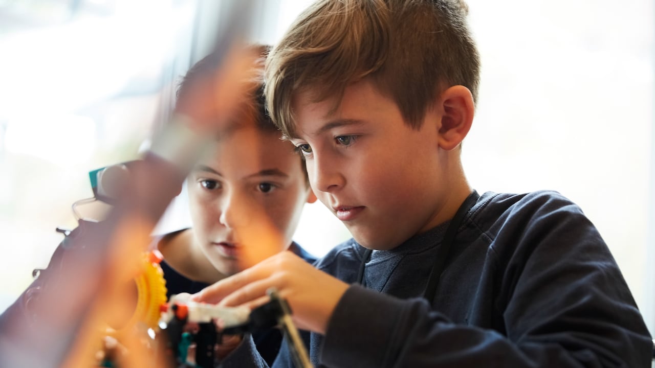 Estudiantes varones que trabajan con robot para proyectos científicos en el aula