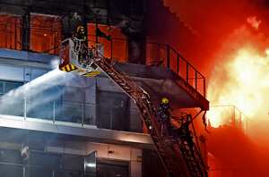 A resident waits on a balcony to be rescued as firefighters battle a huge fire raging through a multistorey residential block in Valencia on February 22, 2024. Spanish firefighters were battling a huge fire raging through a multistorey residential block in the eastern port city of Valencia today, the emergency services said. Flames and vast clouds of black smoke engulfed the building, with 22 teams of firefighters battling high winds to tackle the blaze, the 112 emergency services said. In a post on X, formerly Twitter, the emergency services said seven people had been lightly injured: a minor, three adults and three firefighters, most of them suffering from smoke inhalation. (Photo by Jose Jordan / AFP)