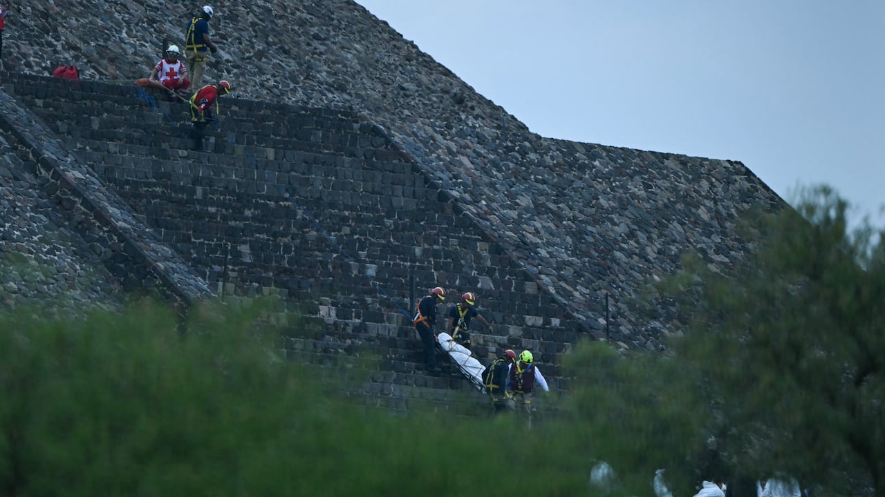 Expertos forenses y miembros de la Cruz Roja trasladan un cuerpo a la Pirámide de la Luna en la zona arqueológica de Teotihuacán tras un tiroteo ocurrido en Teotihuacán
