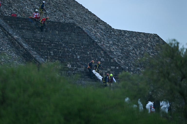 Expertos forenses y miembros de la Cruz Roja trasladan un cuerpo a la Pirámide de la Luna en la zona arqueológica de Teotihuacán tras un tiroteo ocurrido en Teotihuacán