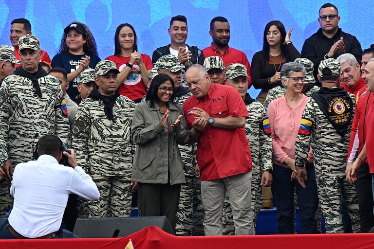 La presidenta interina de Venezuela, Delcy Rodríguez (C, izquierda), escucha al ministro del Interior, Justicia y Paz, Diosdado Cabello, durante un desfile cívico-militar