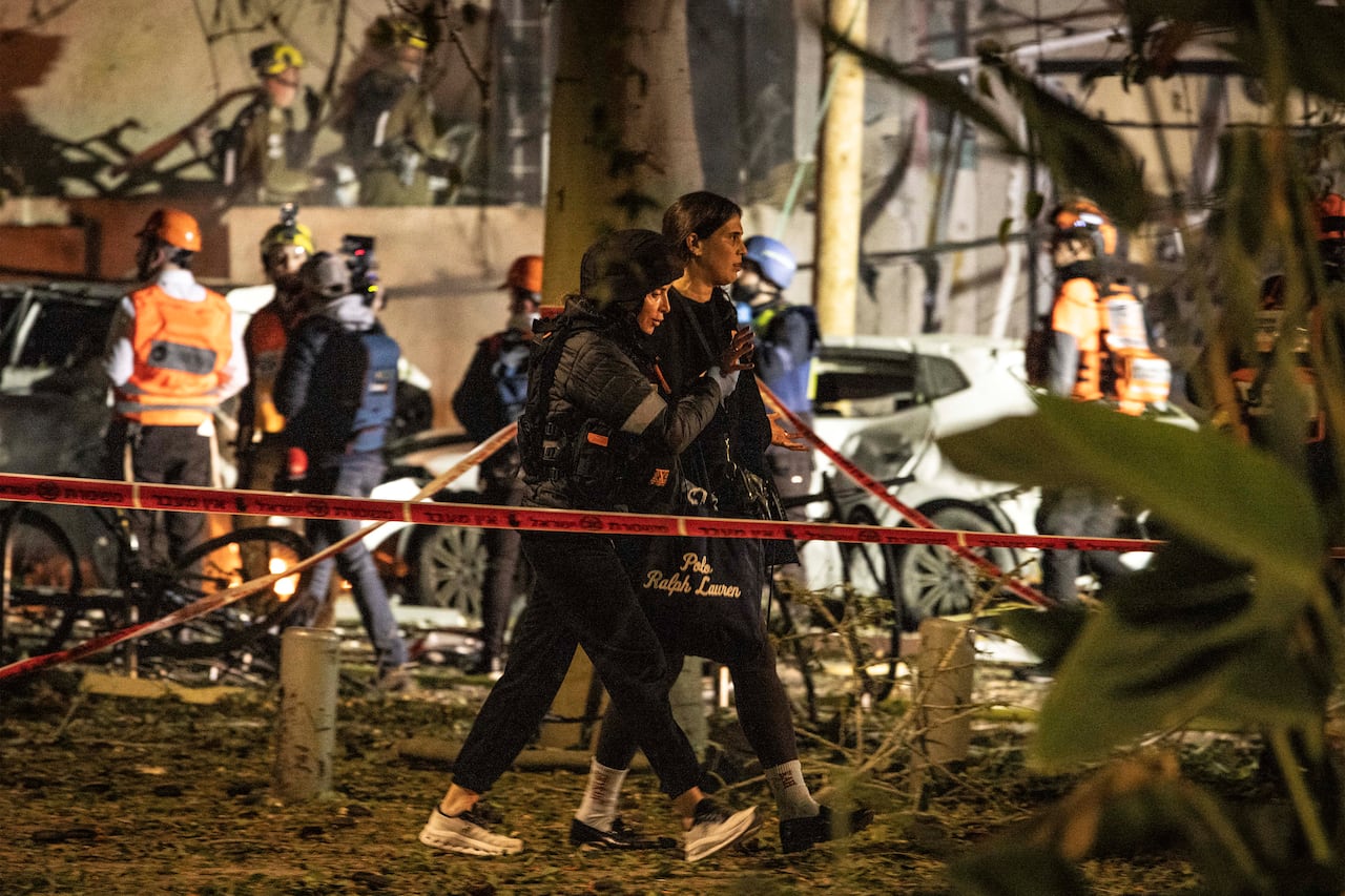 Una mujer herida es escoltada a un lugar seguro en el lugar de un ataque con misiles iraníes en Tel Aviv el 28 de febrero de 2026. Estados Unidos e Israel lanzaron ataques contra Irán el 28 de febrero