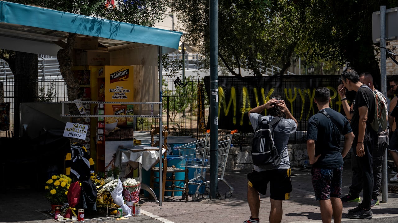 Personas que transitan por Atenas observan el homenaje al hincha fallecido.