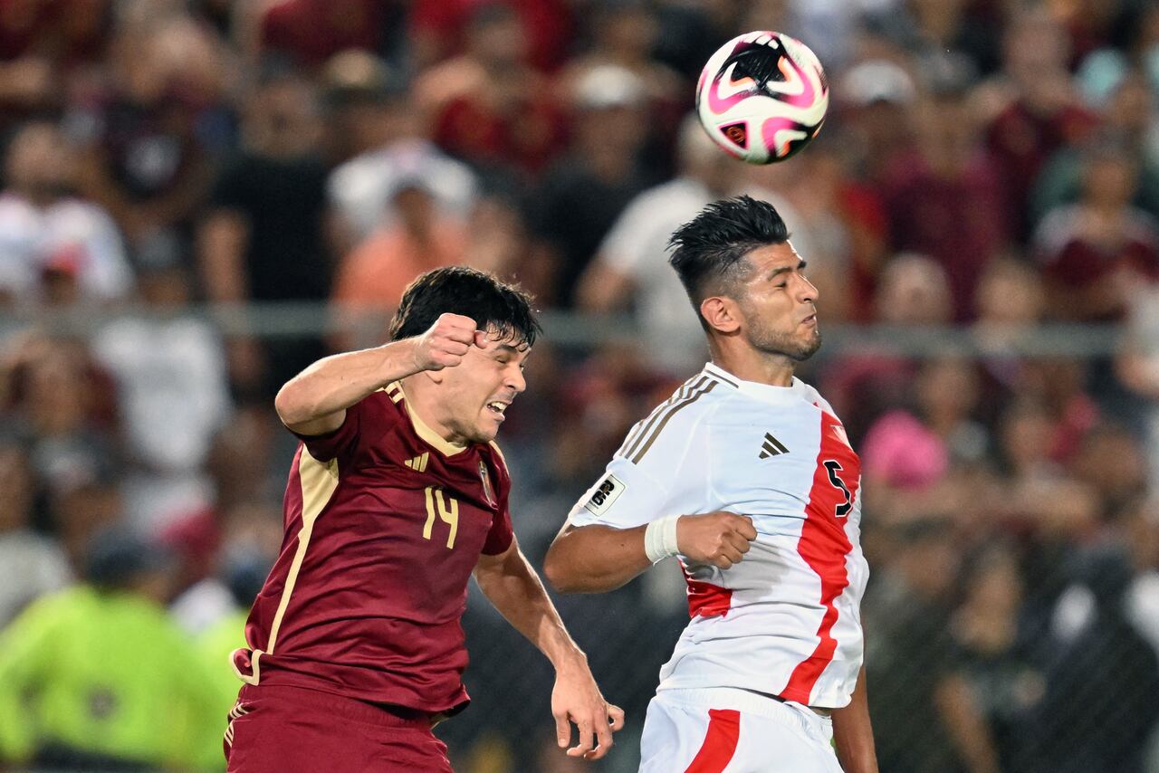 El defensor #14 de Venezuela Jon Aramburu y el defensor #05 de Perú Carlos Zambrano saltan para cabecear el balón.