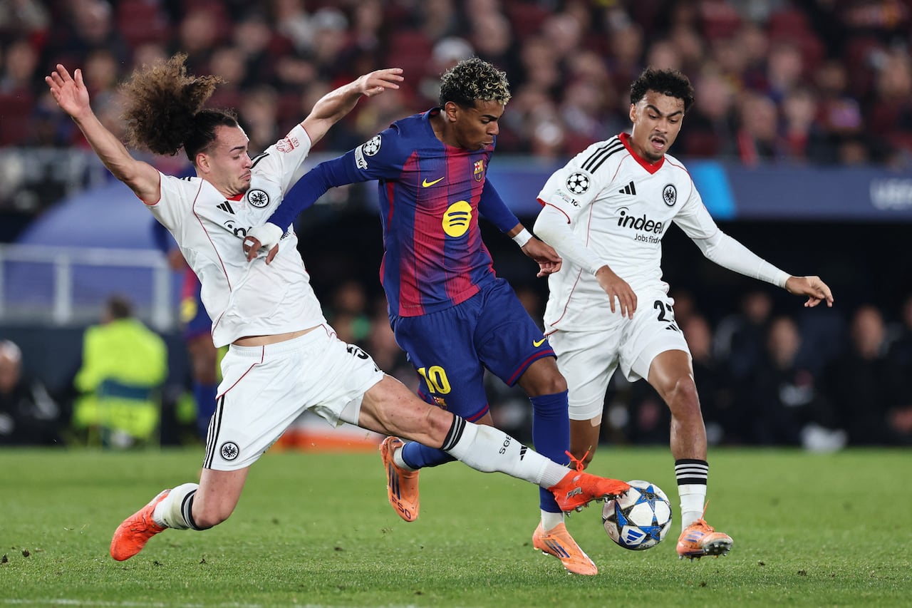 (De izq. a der.) El defensa belga #03 del Frankfurt, Arthur Theate, el delantero español #10 del Barcelona, Lamine Yamal, y el defensa alemán #21 del Frankfurt, Nathaniel Brown, disputan el balón durante el partido de la sexta jornada de la fase de liga de la UEFA Champions League entre el FC Barcelona y el Eintracht Frankfurt en el estadio Camp Nou de Barcelona el 9 de diciembre de 2025. (Foto de Josep LAGO / AFP)