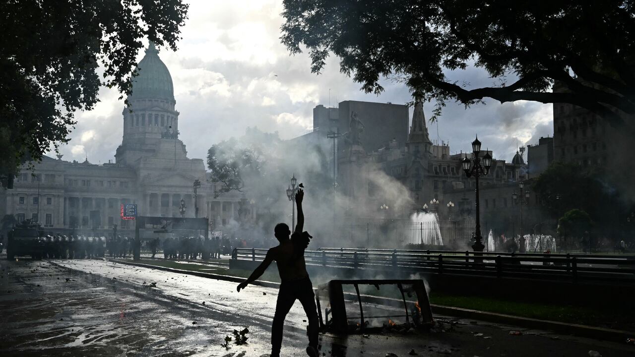 Un manifestante lanza una piedra mientras se enfrenta a la policía antidisturbios durante una protesta de jubilados, apoyada por aficionados al fútbol, contra el gobierno del presidente Javier Milei en Buenos Aires el 12 de marzo de 2025.