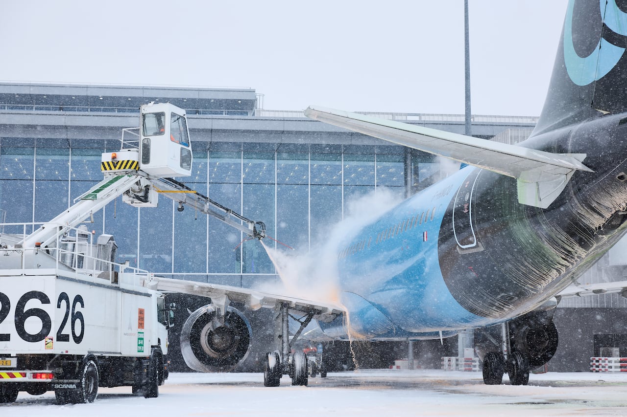 Empleados trabajan para descongelar un avión en la pista tras las fuertes nevadas que provocaron la cancelación de vuelos en el aeropuerto de Orly, al sur de París, el 7 de enero de 2026.
