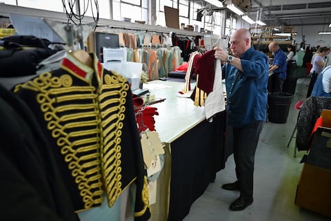 Un trabajador inspecciona un uniforme de abrigo dorado de la Caballería Doméstica que se usará durante la Coronación del Rey Carlos III de Gran Bretaña y su esposa Camilla de Gran Bretaña, Reina Consorte.