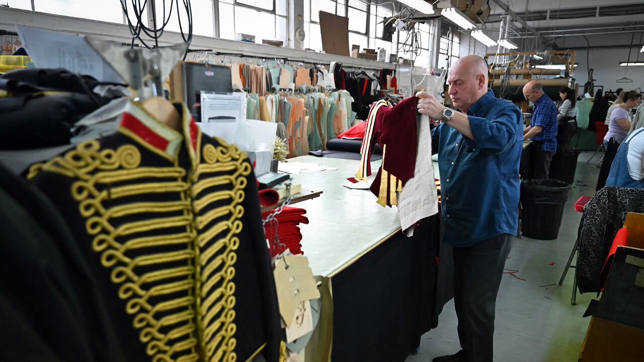 Un trabajador inspecciona un uniforme de abrigo dorado de la Caballería Doméstica que se usará durante la Coronación del Rey Carlos III de Gran Bretaña y su esposa Camilla de Gran Bretaña, Reina Consorte.