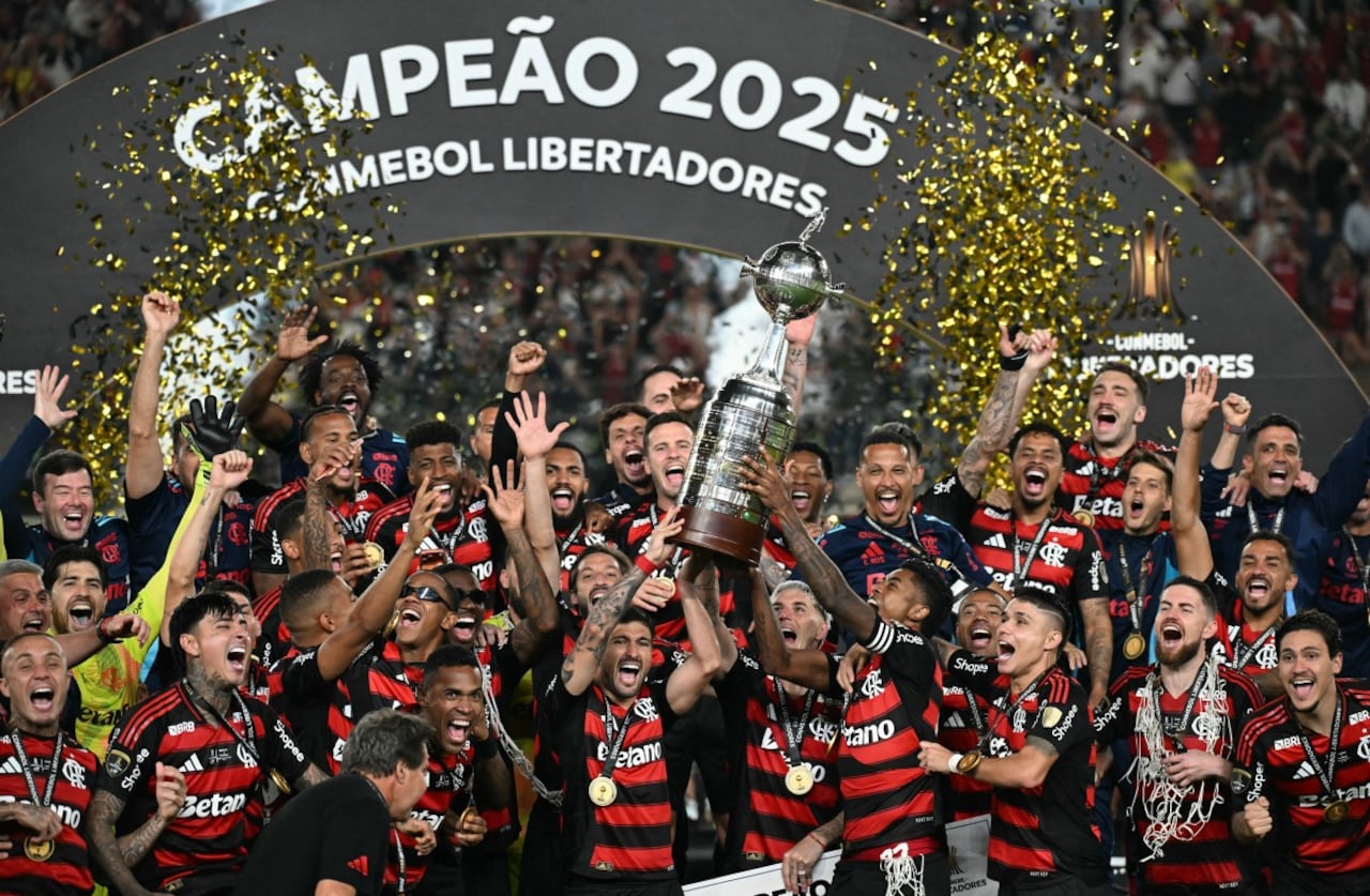 El delantero #27 del Flamengo, Bruno Henrique (D), y el mediocampista uruguayo #10 Giorgian de Arrascaeta (I) levantan el trofeo con sus compañeros de equipo después de ganar el partido final de la Copa Libertadores de Brasil.
