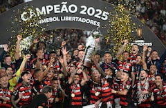 El delantero #27 del Flamengo, Bruno Henrique (D), y el mediocampista uruguayo #10 Giorgian de Arrascaeta (I) levantan el trofeo con sus compañeros de equipo después de ganar el partido final de la Copa Libertadores de Brasil.