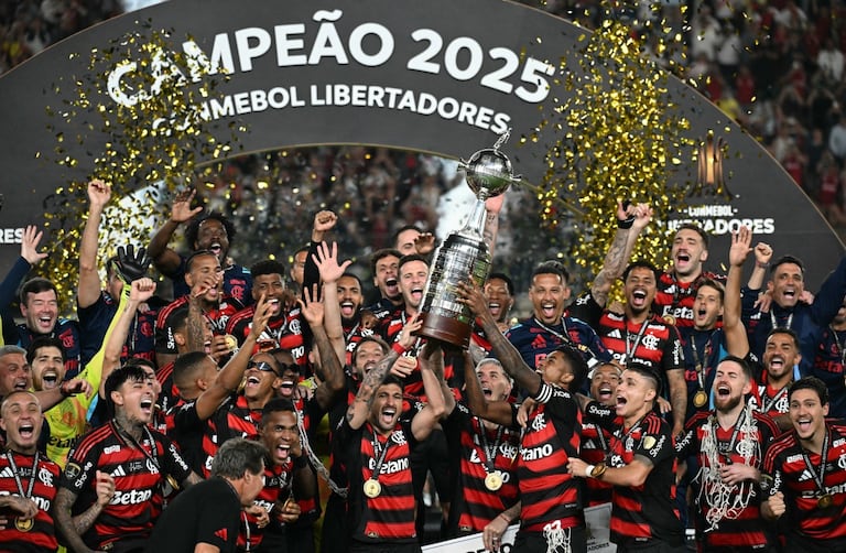 El delantero #27 del Flamengo, Bruno Henrique (D), y el mediocampista uruguayo #10 Giorgian de Arrascaeta (I) levantan el trofeo con sus compañeros de equipo después de ganar el partido final de la Copa Libertadores de Brasil.