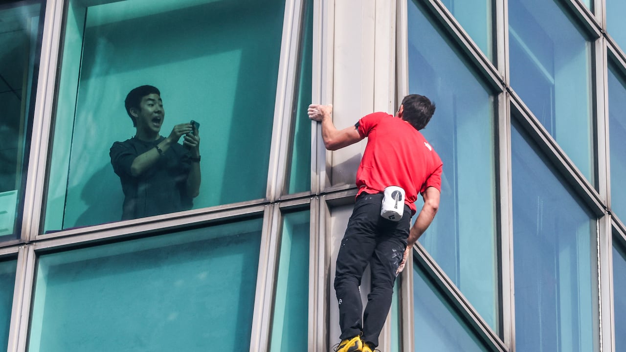 Un ocupante del edificio graba con su teléfono al escalador estadounidense Alex Honnold mientras escala el edificio Taipei 101 sin cuerdas ni equipo de seguridad en Taipéi el 25 de enero de 2026. (Foto de I-Hwa Cheng / AFP)
