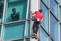 Un ocupante del edificio graba con su teléfono al escalador estadounidense Alex Honnold mientras escala el edificio Taipei 101 sin cuerdas ni equipo de seguridad en Taipéi el 25 de enero de 2026. (Foto de I-Hwa Cheng / AFP)