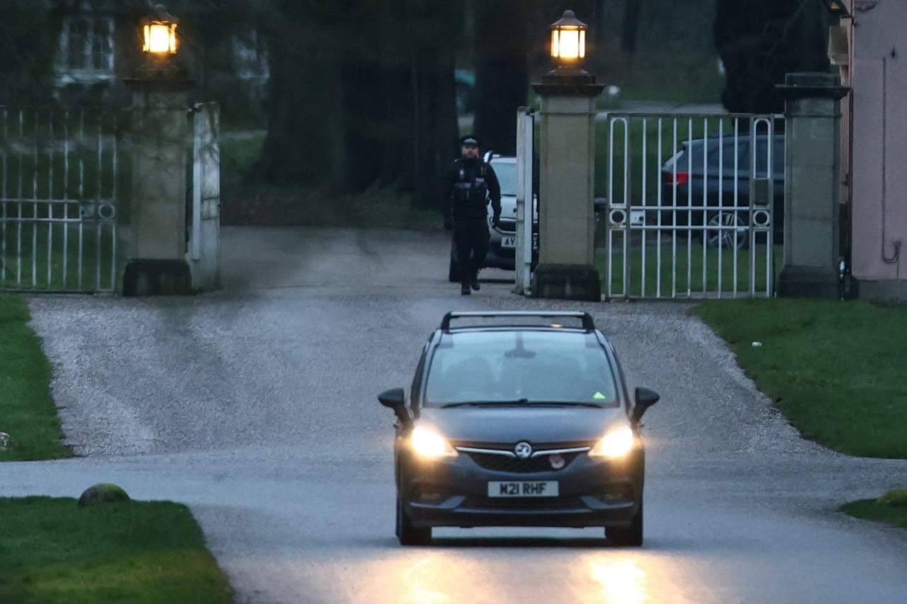 Se muestra a un policía en la entrada del Royal Lodge, una propiedad de 30 habitaciones y antigua residencia del ex príncipe británico Andrew, mientras un coche se aleja en Windsor Great Park en Windsor, Berkshire el 19 de febrero de 2026, que supuestamente fue registrado por la policía mientras Andrew era arrestado más temprano ese día en la finca privada de Sandringham del rey en Norfolk. La familia real británica estaba en crisis el 19 de febrero, ya que el ex príncipe Andrew estaba bajo custodia policial tras ser arrestado por sospecha de conducta indebida por sus vínculos con el fallecido delincuente sexual estadounidense Jeffrey Epstein. (Foto de Toby Shepheard / AFP)