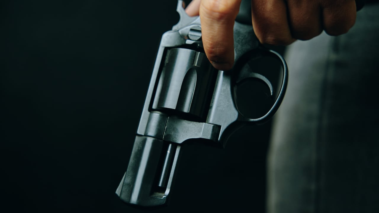 Criminal con revólver sobre fondo oscuro