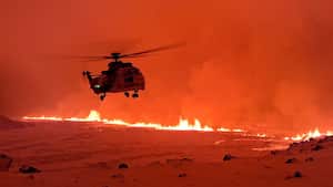 This handout image shows an Icelandic Coast Guard helicopter overflying an volcanic eruption on the Reykjanes peninsula 3 km north of Grindavik, western Iceland on December 19, 2023. A volcanic eruption began on Monday night in Iceland, south of the capital Reykjavik, following an earthquake swarm, Iceland's Meteorological Office reported. (Photo by Icelandic Coast Guard / HANDOUT / AFP) / RESTRICTED TO EDITORIAL USE - MANDATORY CREDIT "AFP PHOTO /   " - NO MARKETING NO ADVERTISING CAMPAIGNS - DISTRIBUTED AS A SERVICE TO CLIENTS