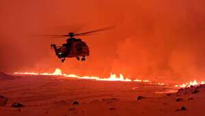 This handout image shows an Icelandic Coast Guard helicopter overflying an volcanic eruption on the Reykjanes peninsula 3 km north of Grindavik, western Iceland on December 19, 2023. A volcanic eruption began on Monday night in Iceland, south of the capital Reykjavik, following an earthquake swarm, Iceland's Meteorological Office reported. (Photo by Icelandic Coast Guard / HANDOUT / AFP) / RESTRICTED TO EDITORIAL USE - MANDATORY CREDIT "AFP PHOTO / " - NO MARKETING NO ADVERTISING CAMPAIGNS - DISTRIBUTED AS A SERVICE TO CLIENTS