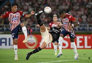 El defensa de Universitario Marcos Saravia (C) patea el balón entre el delantero de Junior Carlos Bacca (L) y el centrocampista Carlos Cantillo durante el partido de fútbol de ida de la fase de grupos de la Copa Libertadores entre Junior de Colombia y Universitario de Perú en el estadio Metropolitano Roberto Meléndez de Barranquilla.