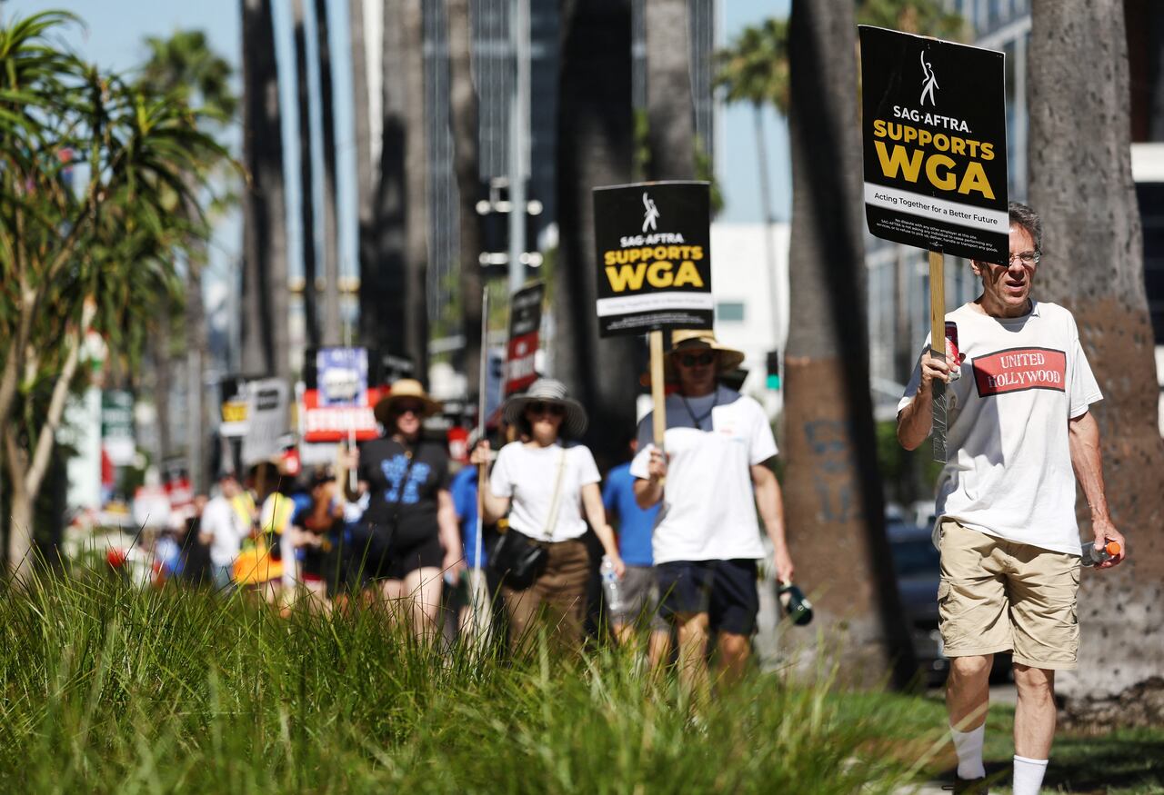LOS ANGELES, CALIFORNIA - JULY 13: A sign reads 'SAG-AFTRA Supports WGA' as SAG-AFTRA members walk the picket line in solidarity with striking WGA (Writers Guild of America) workers outside Netflix offices on July 13, 2023 in Los Angeles, California. Members of SAG-AFTRA, Hollywood�s largest union which represents actors and other media professionals, will join striking WGA (Writers Guild of America) workers at midnight in the first joint walkout against the studios since 1960. The strike could shut down Hollywood productions completely with writers in the third month of their strike against the Hollywood studios.   Mario Tama/Getty Images/AFP (Photo by MARIO TAMA / GETTY IMAGES NORTH AMERICA / Getty Images via AFP)